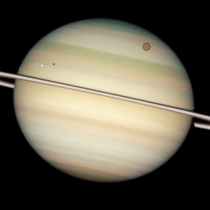 This image of Saturn was taken by the Hubble Space Telescope along with four of its moons, two of which are causing an eclipse.